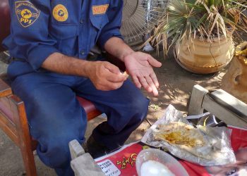 Long hours, low wages, and little dignity — a security guard pauses on duty to eat a simple, makeshift meal of roti with curry and a bowl of watery yogurt, placed on a worn bench in the open. With no proper dining space, no rest breaks, and minimal facilities, this scene reflects the daily reality of many guards in Pakistan who work exhausting shifts yet struggle to afford even a basic, nutritious meal.
